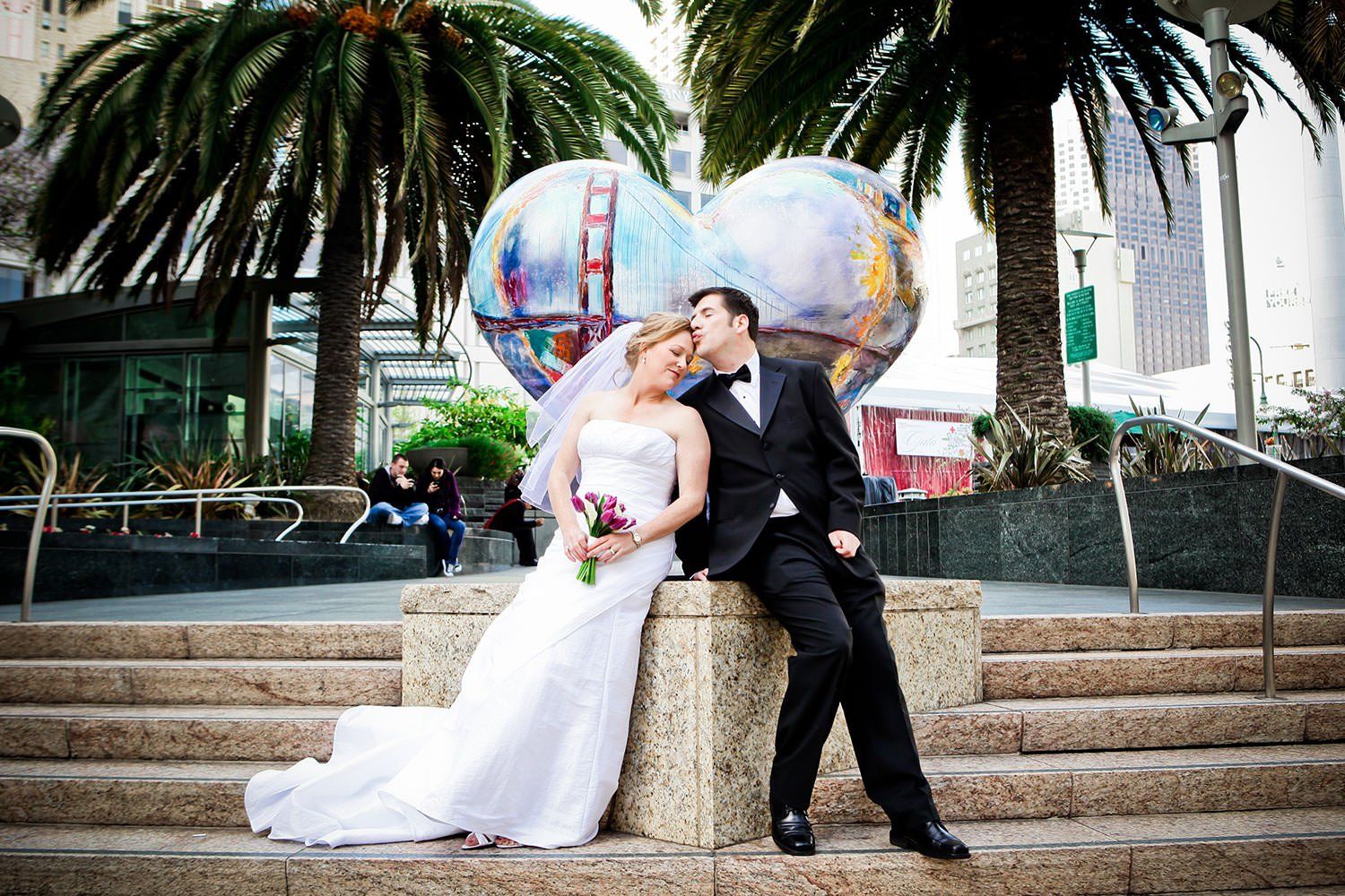 A bride and groom are posing for a picture on a set of stairs.