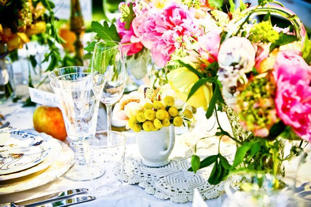 A table with plates , glasses , and flowers on it.