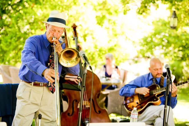 A man is playing a trumpet and a man is playing a guitar.