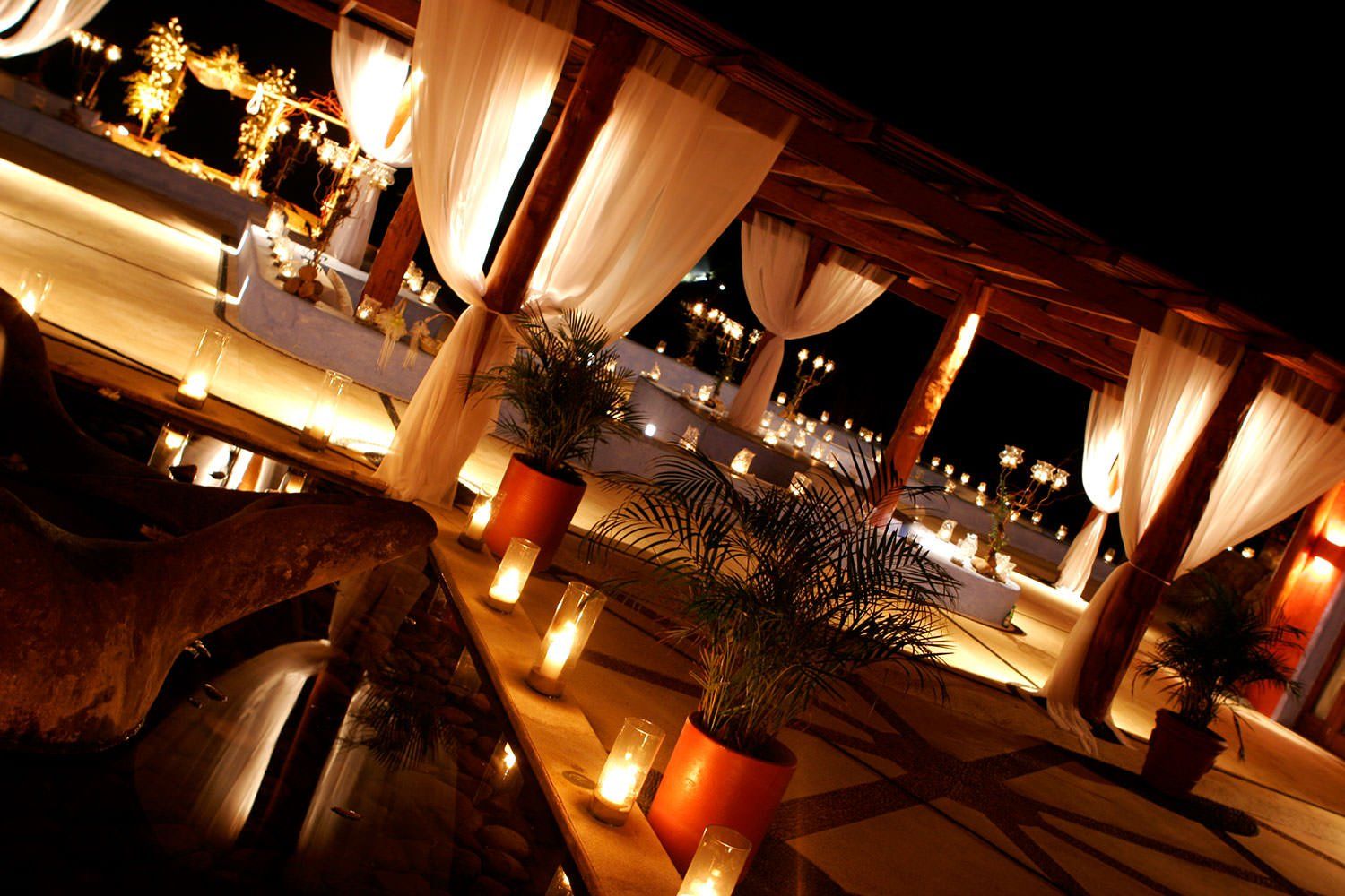 A patio area with candles and curtains at night