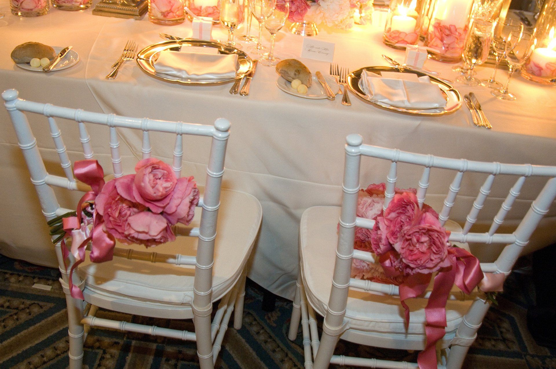 Two chairs are decorated with pink flowers and ribbons