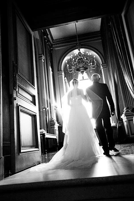 A black and white photo of a bride and groom walking down stairs.