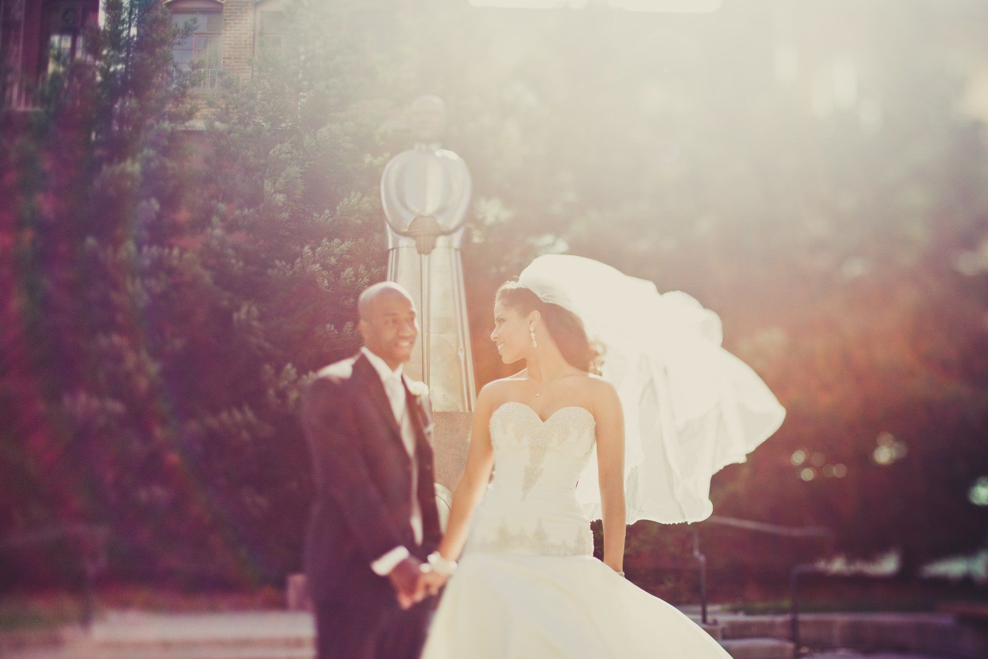 A bride and groom are holding hands while the bride 's veil blows in the wind.