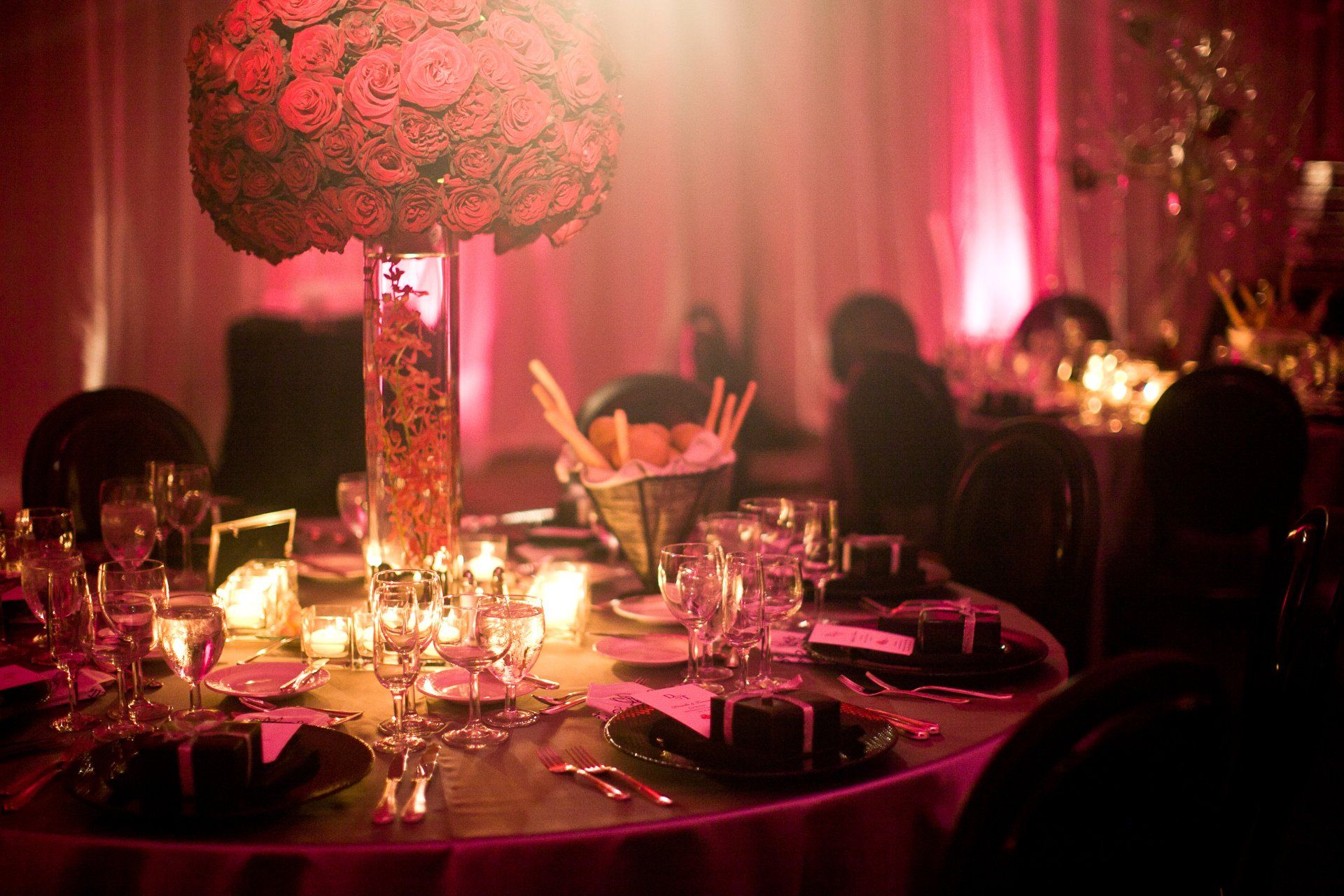 A table set for a wedding reception with a vase of flowers on it.