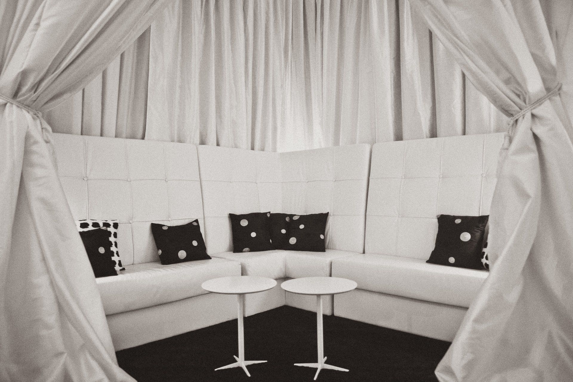A black and white photo of a living room with white curtains