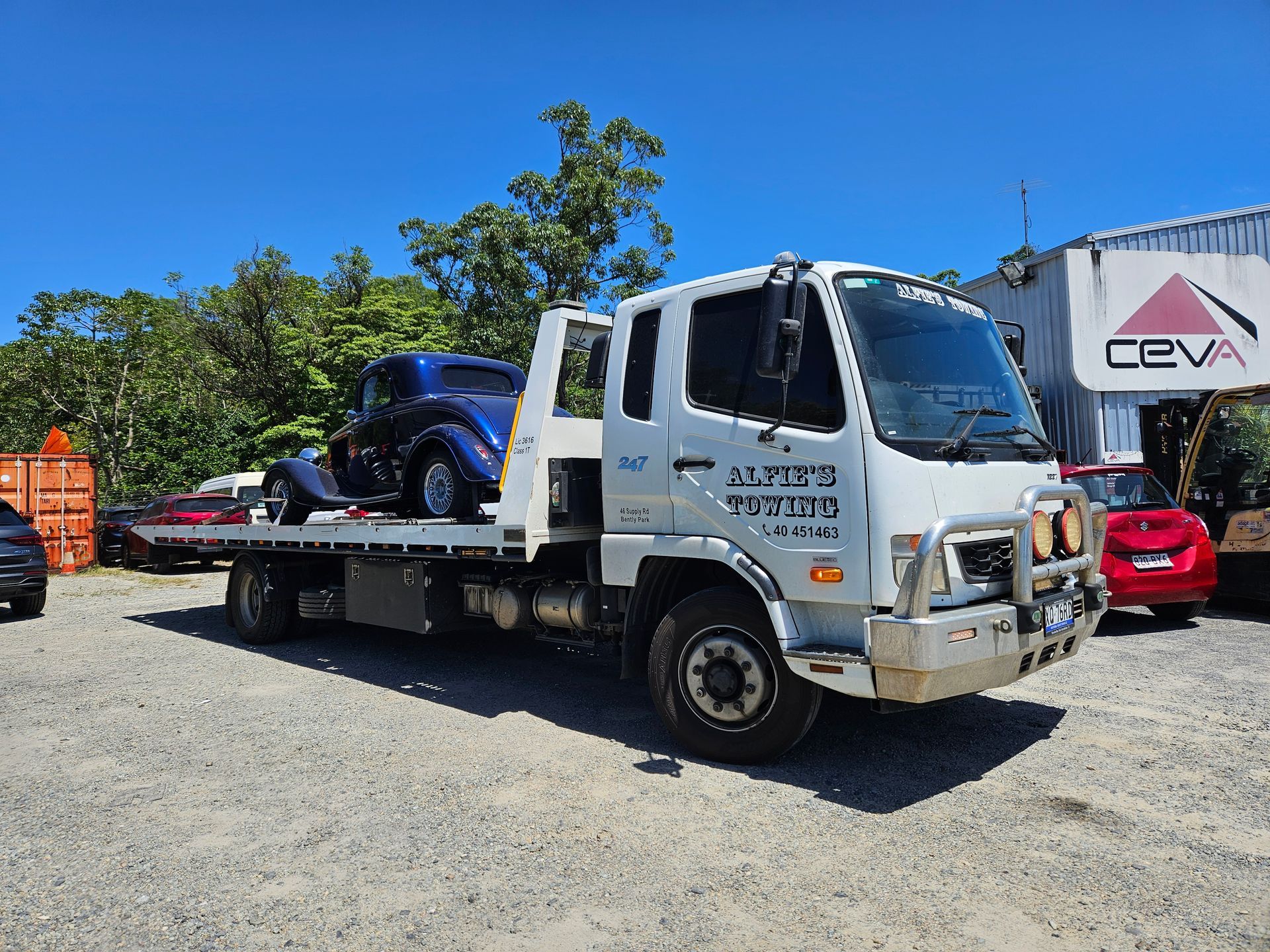 White Tow Truck Carrying a Blue Classic Car — Alfie's Towing in Kuranda, QLD