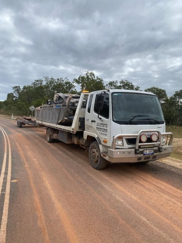 White Flatbed Truck on a Red Dirt Road, Towing Equipment Under a Cloudy Sky — Alfie's Towing in Bentley Park, QLD