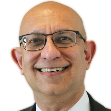 A bald person wearing dark-rimmed glasses smiling, centered against a plain white background.