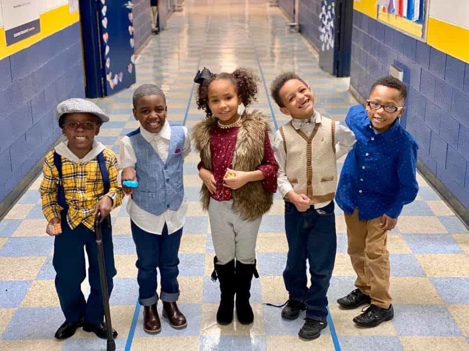 A group of children are posing for a picture in a hallway.