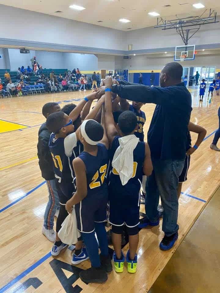 A group of young boys are huddled together on a basketball court.