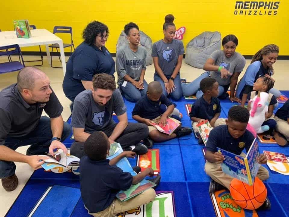 A group of children are sitting on the floor reading books.
