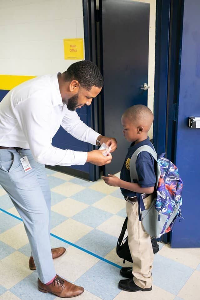 A man is talking to a young boy in a hallway.