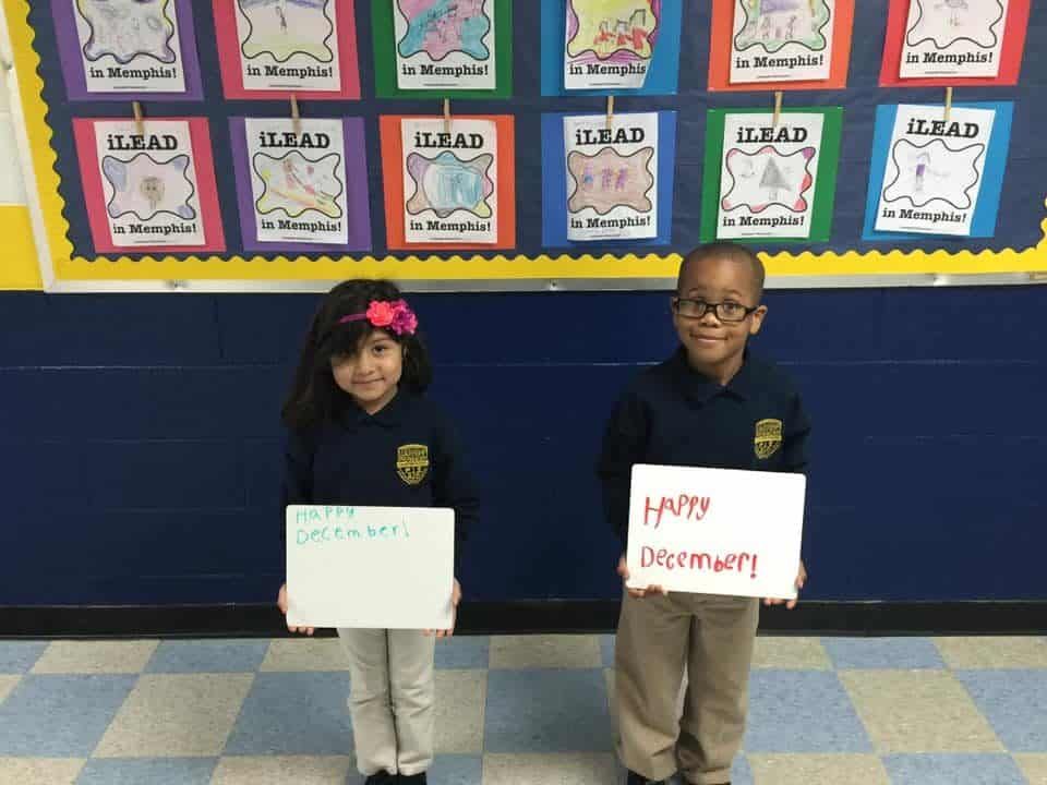 A boy and a girl are holding signs that say happy december