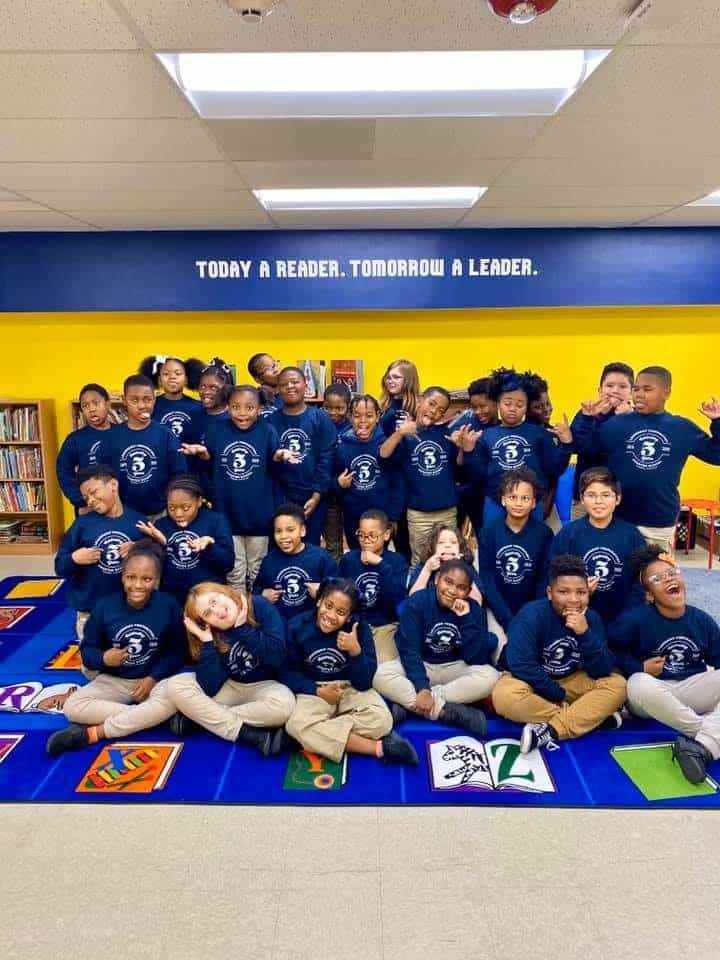 A group of children are posing for a picture in a classroom.