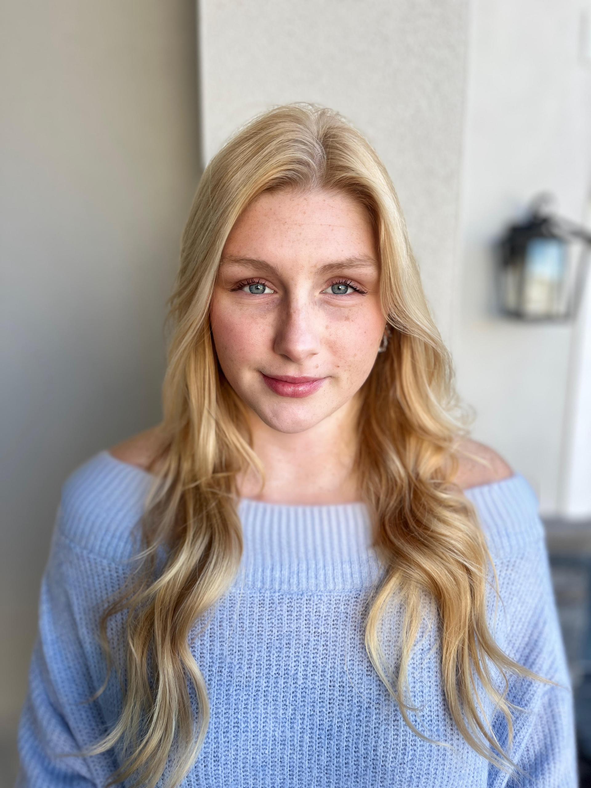 Woman with blonde hair, light blue sweater, looking at the camera.