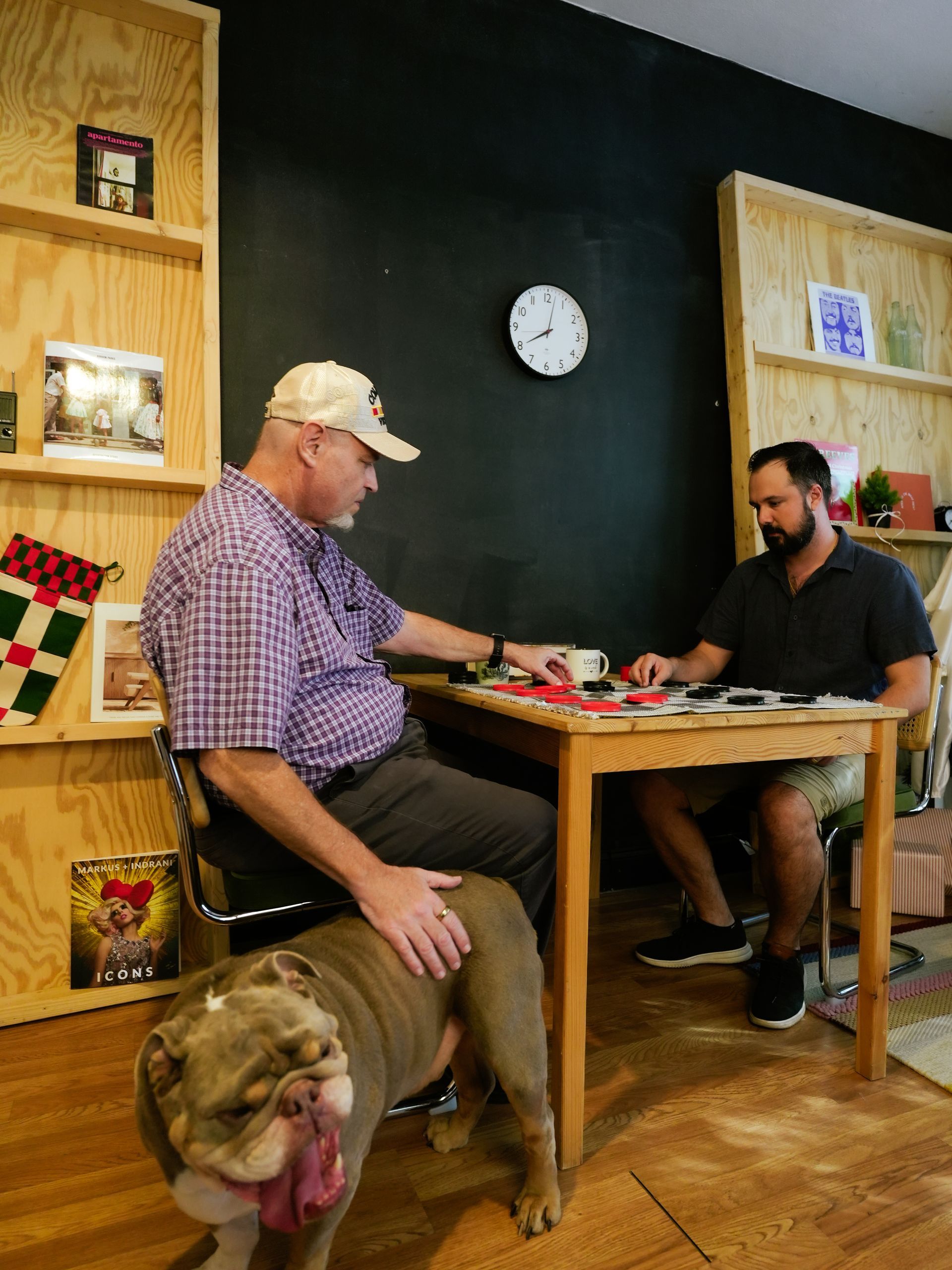 Older woman with cane, being assisted to stand by another person indoors.