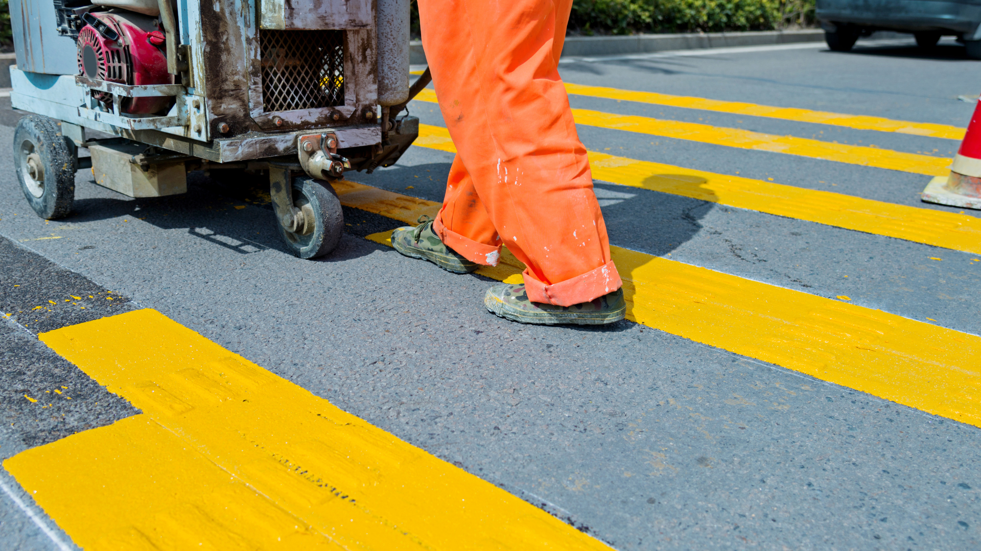 A man is painting yellow lines on a crosswalk.