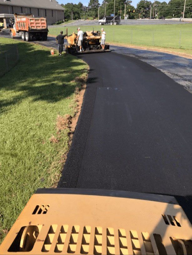 A tractor is laying asphalt on a road