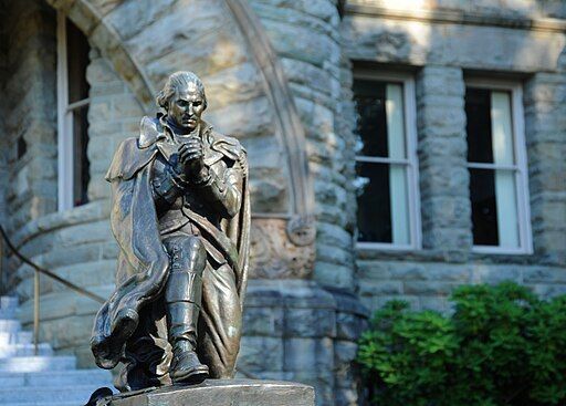 A statue of george washington is in front of a stone building.