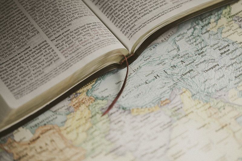 Open Bible with bookmark on top of a world map.