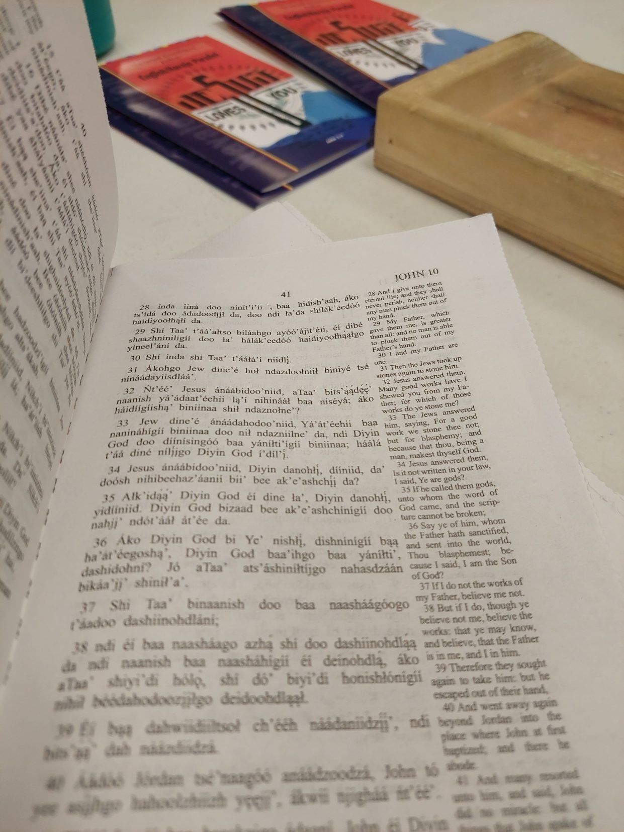 Open book with text, two booklets, and wooden block on a white surface.