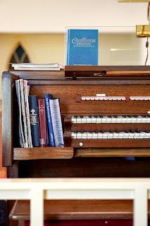 A close up of an organ with books on it in a church.