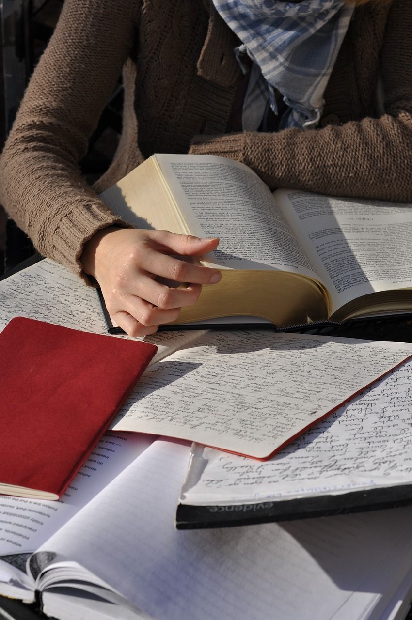 A woman is sitting at a table reading a bible