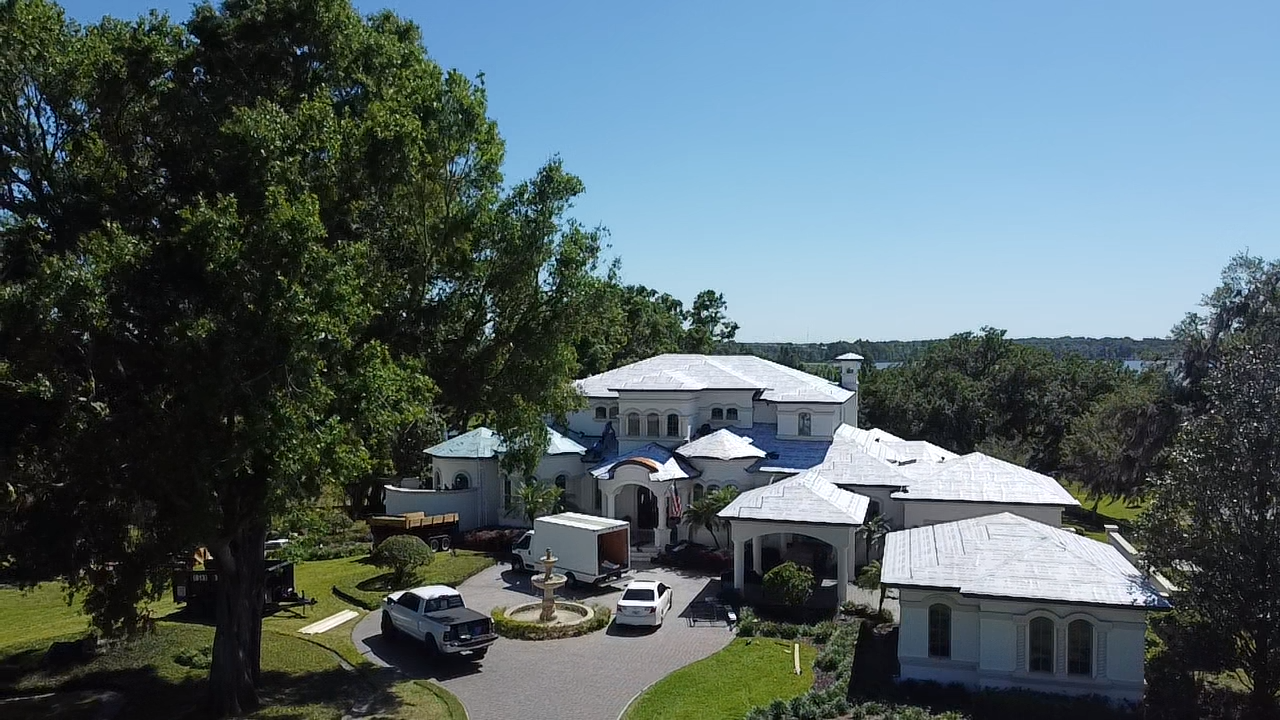 An aerial view of a large white house surrounded by trees.
