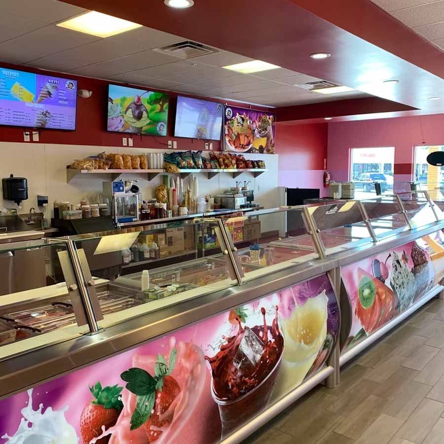 The inside of a restaurant with a long counter filled with ice cream.
