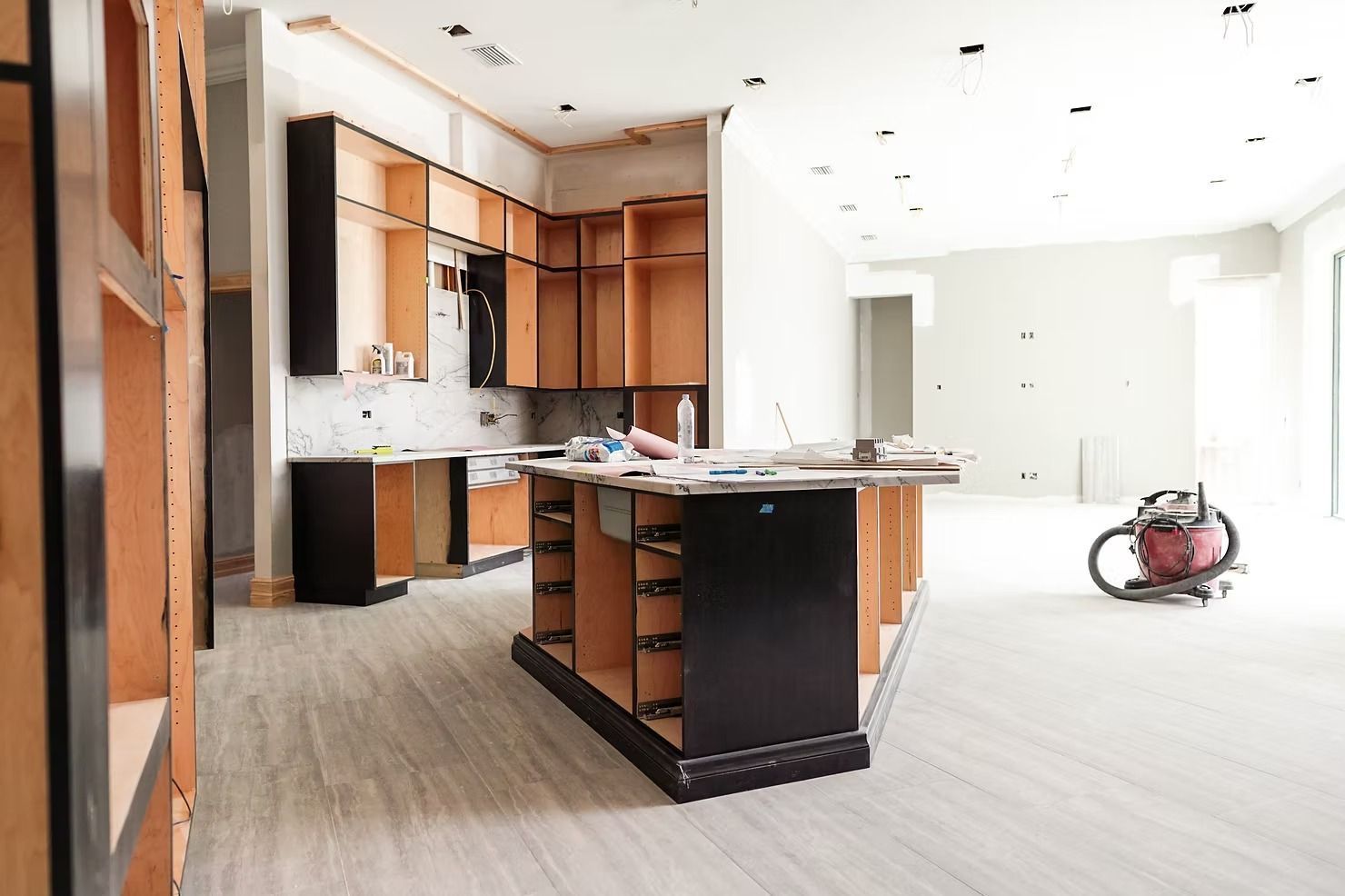 A kitchen under construction with a vacuum cleaner in the middle of the room.