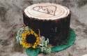 A cake shaped like a tree stump with a sunflower on top.