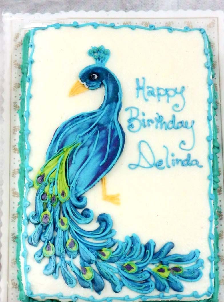 A birthday cake with a peacock on it that says happy birthday delinda