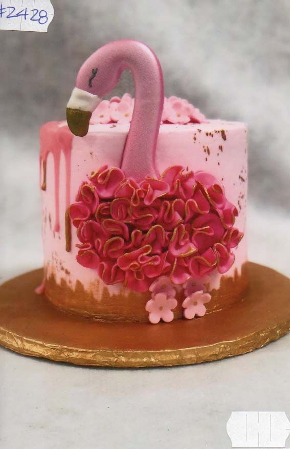 A pink cake with a flamingo on top of it.