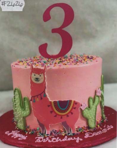 A pink birthday cake with a llama and cactus on it