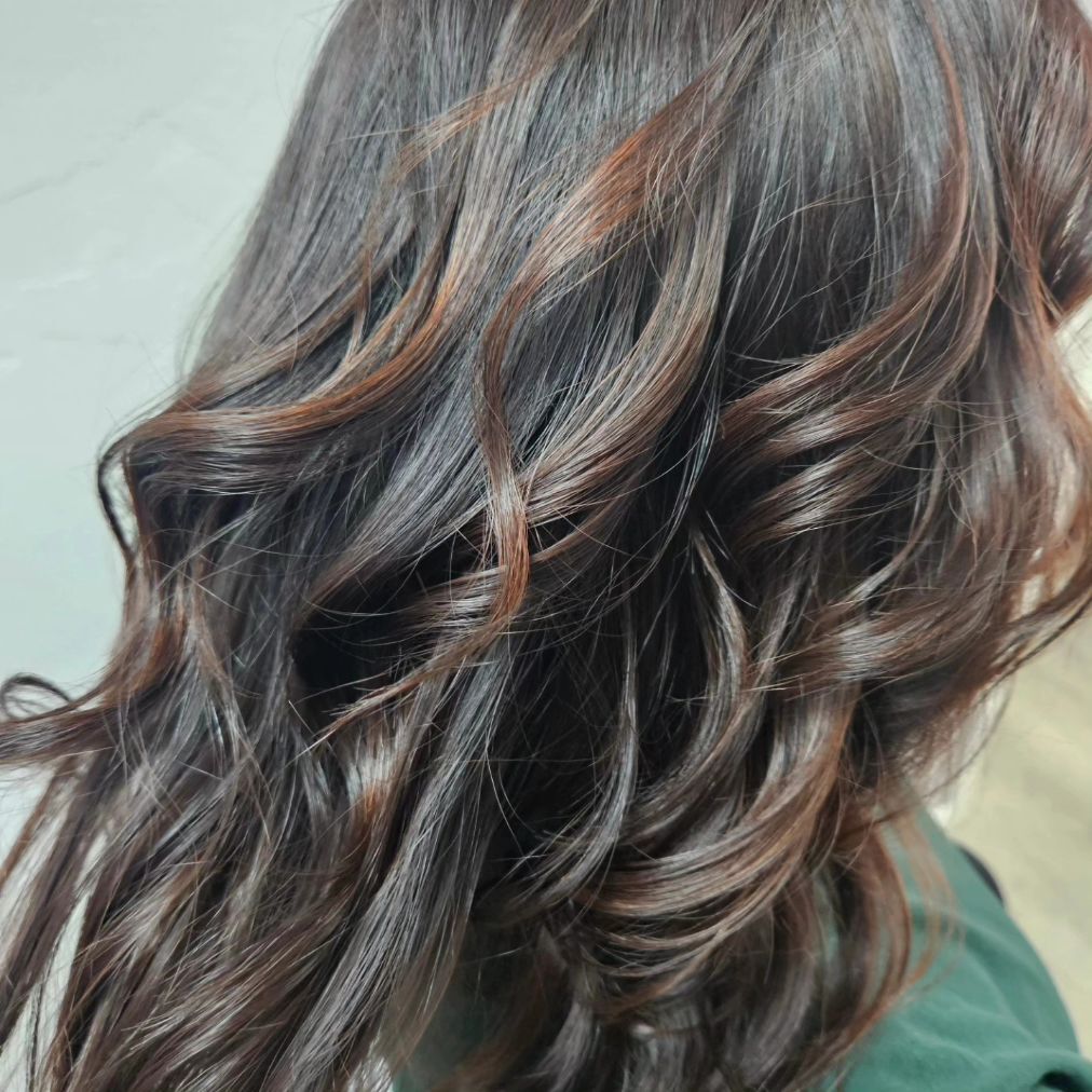 A woman with long brown hair is wearing a green shirt.