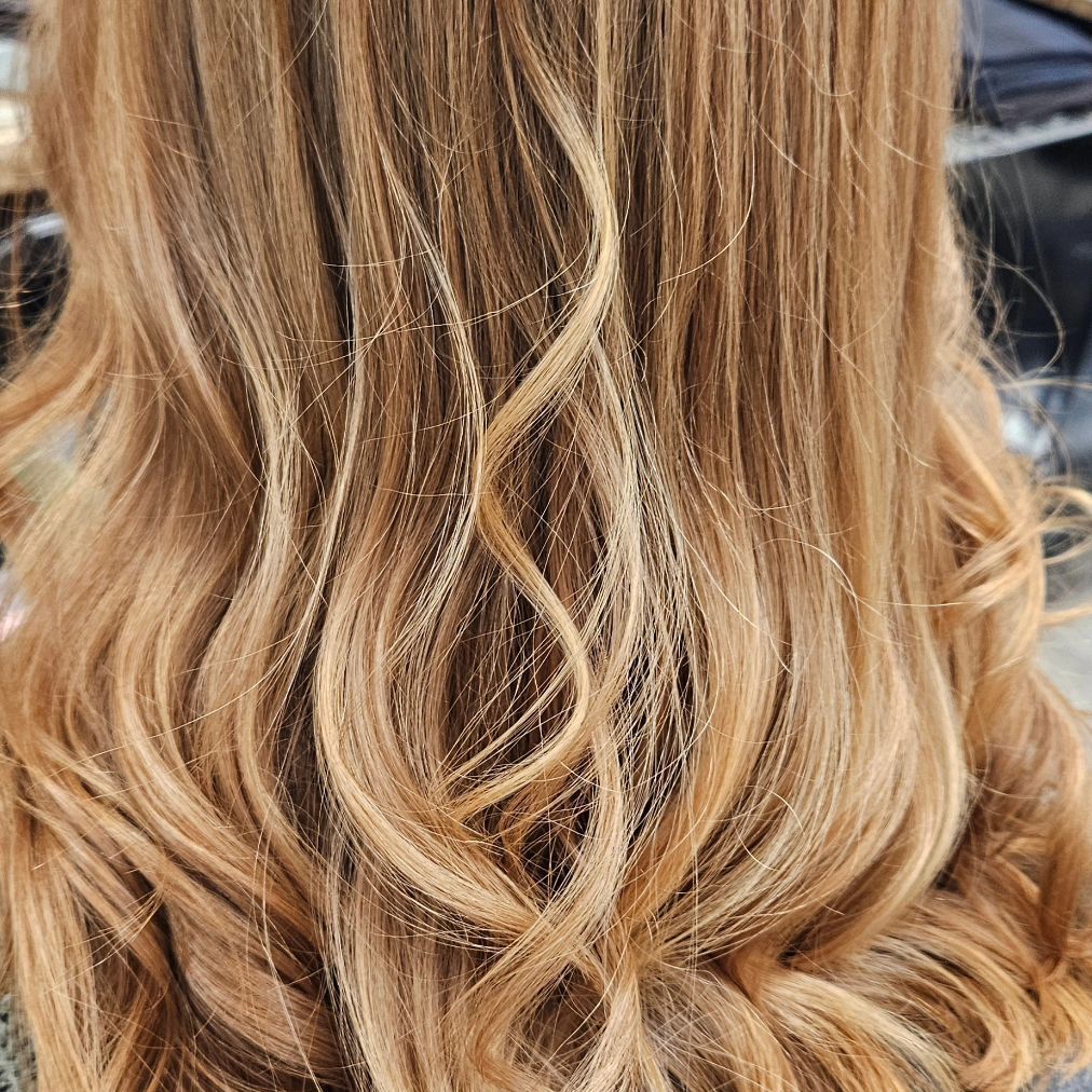 A close up of a woman 's long wavy blonde hair.