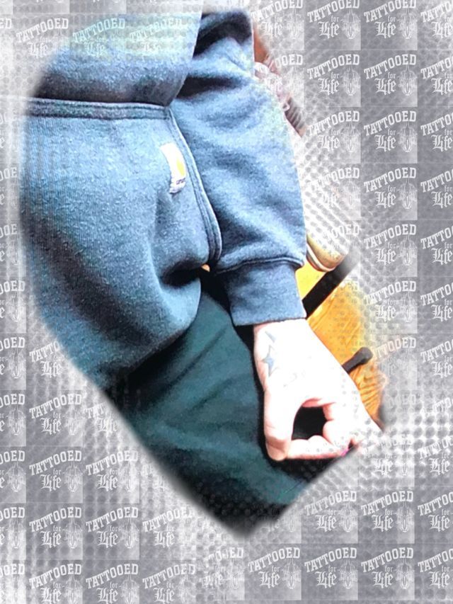 A person with a tattoo on their arm is wearing a blue sweatshirt