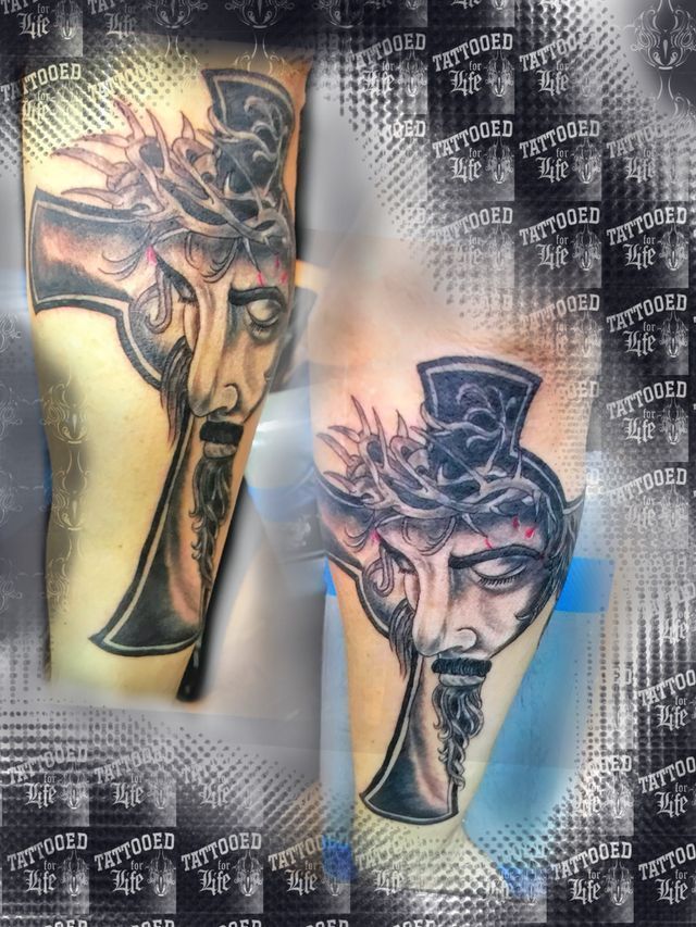 A tattoo of jesus with a cross and crown of thorns on his head.