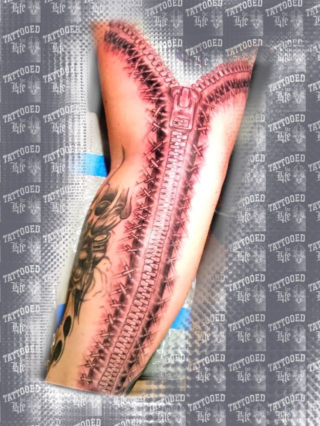 A person has a tattoo of a zipper on their arm