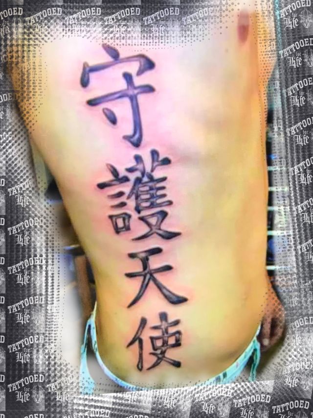A person has a tattoo of chinese characters on their back