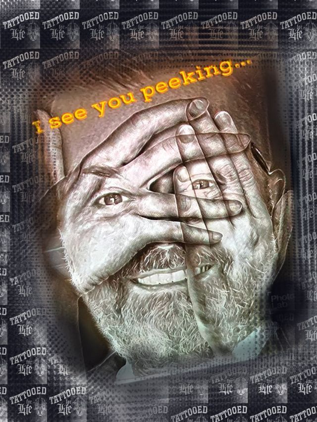 A man with a beard is covering his face with his hands.