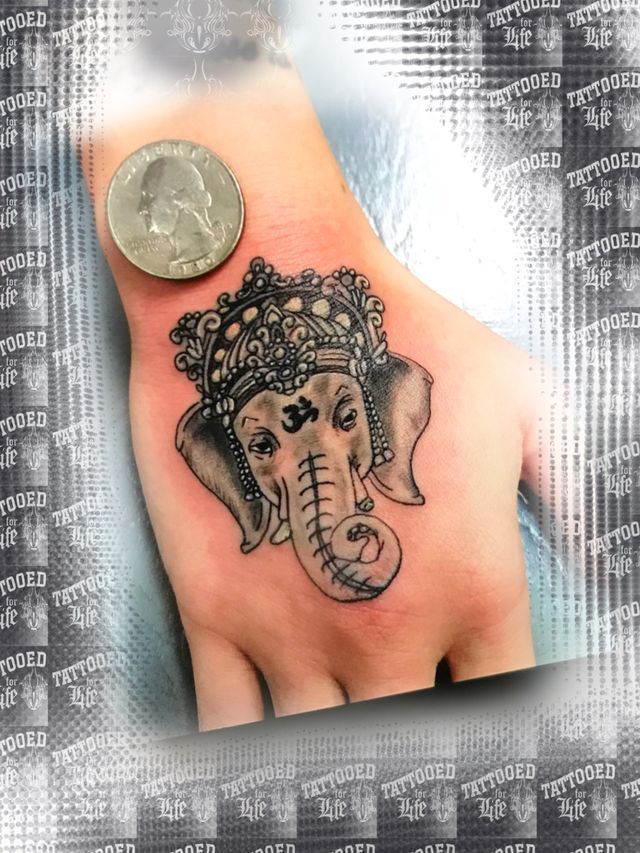 A person has a tattoo of an elephant on their hand next to a quarter.