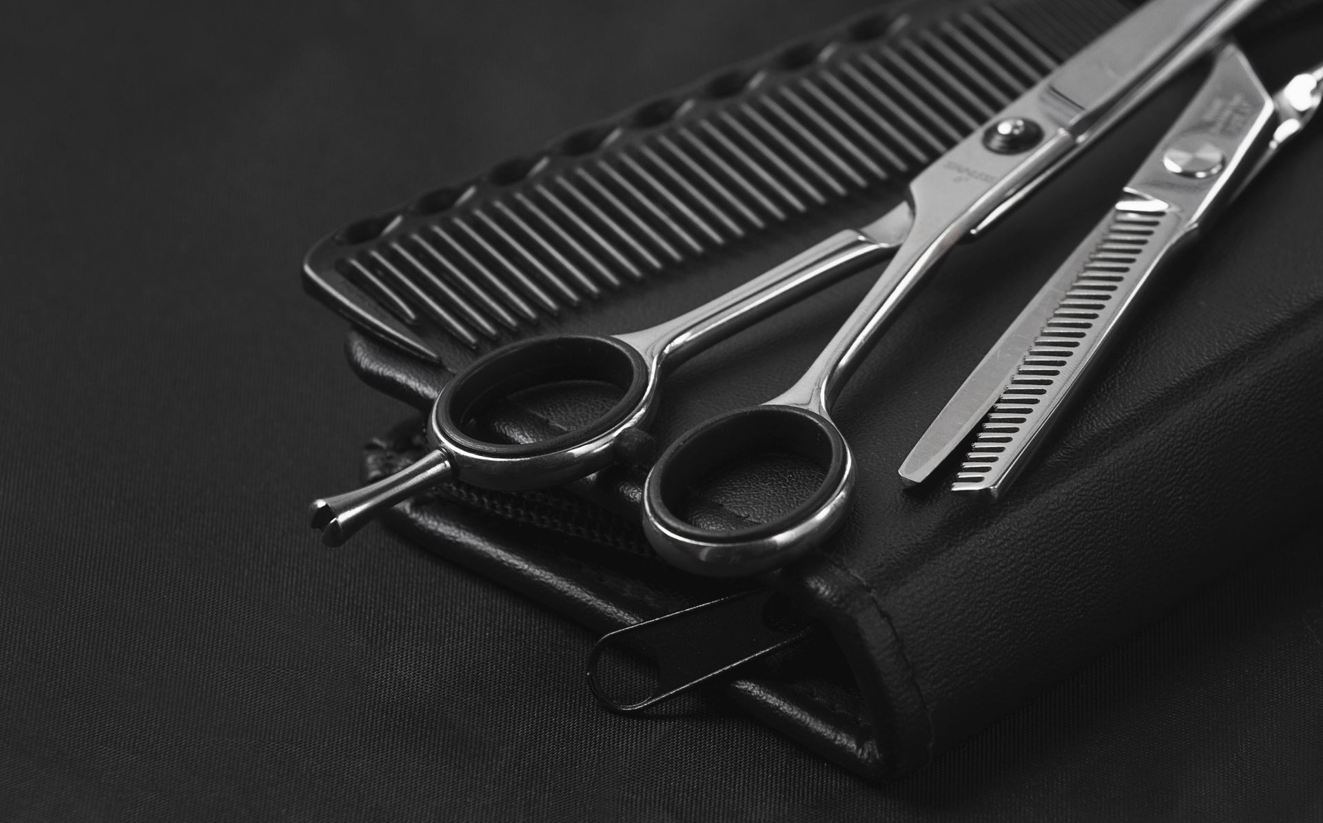 A pair of scissors and a comb on a black surface