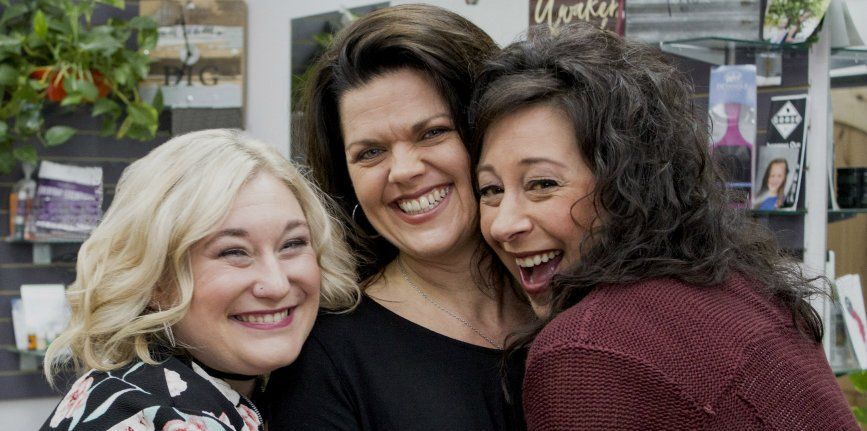 Three women are posing for a picture together and smiling.