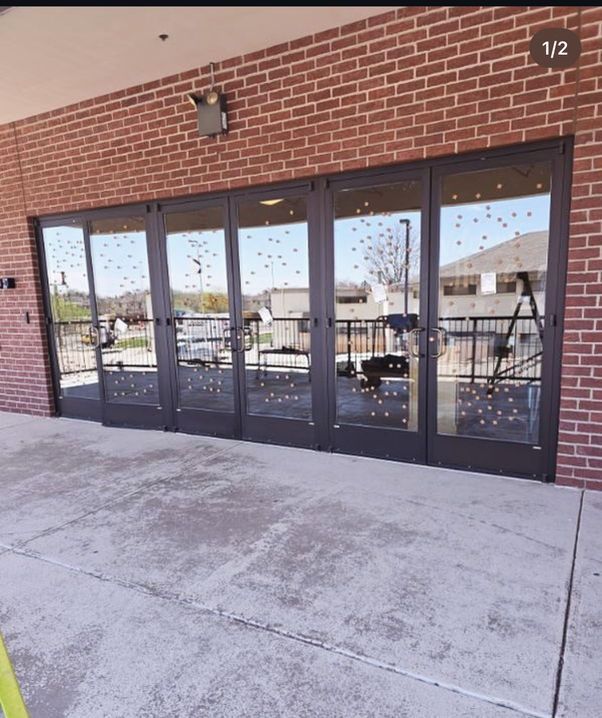 Brick building with multiple glass doors reflecting a sunny outdoor scene.