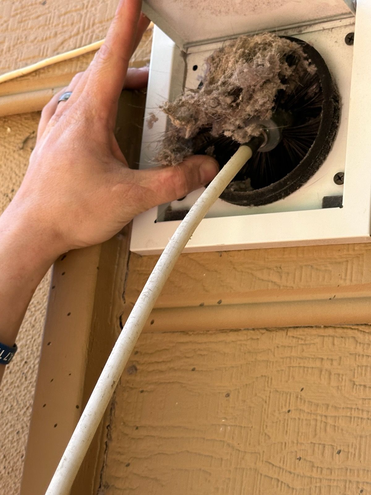 Metal vent on a wall, with a ladder to the right. Building exterior.