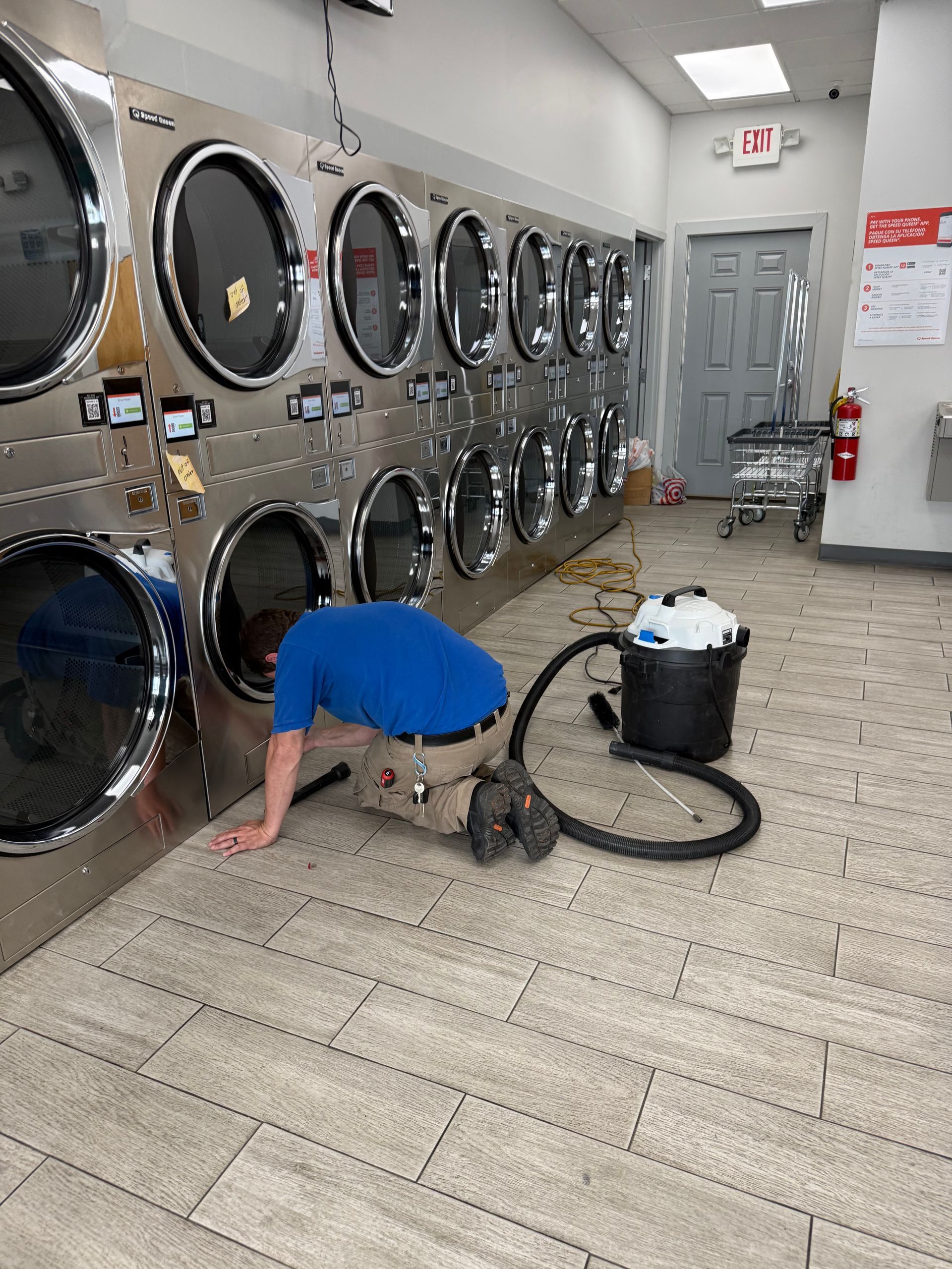 Two industrial dryers with blue laundry, a white wire basket in front.