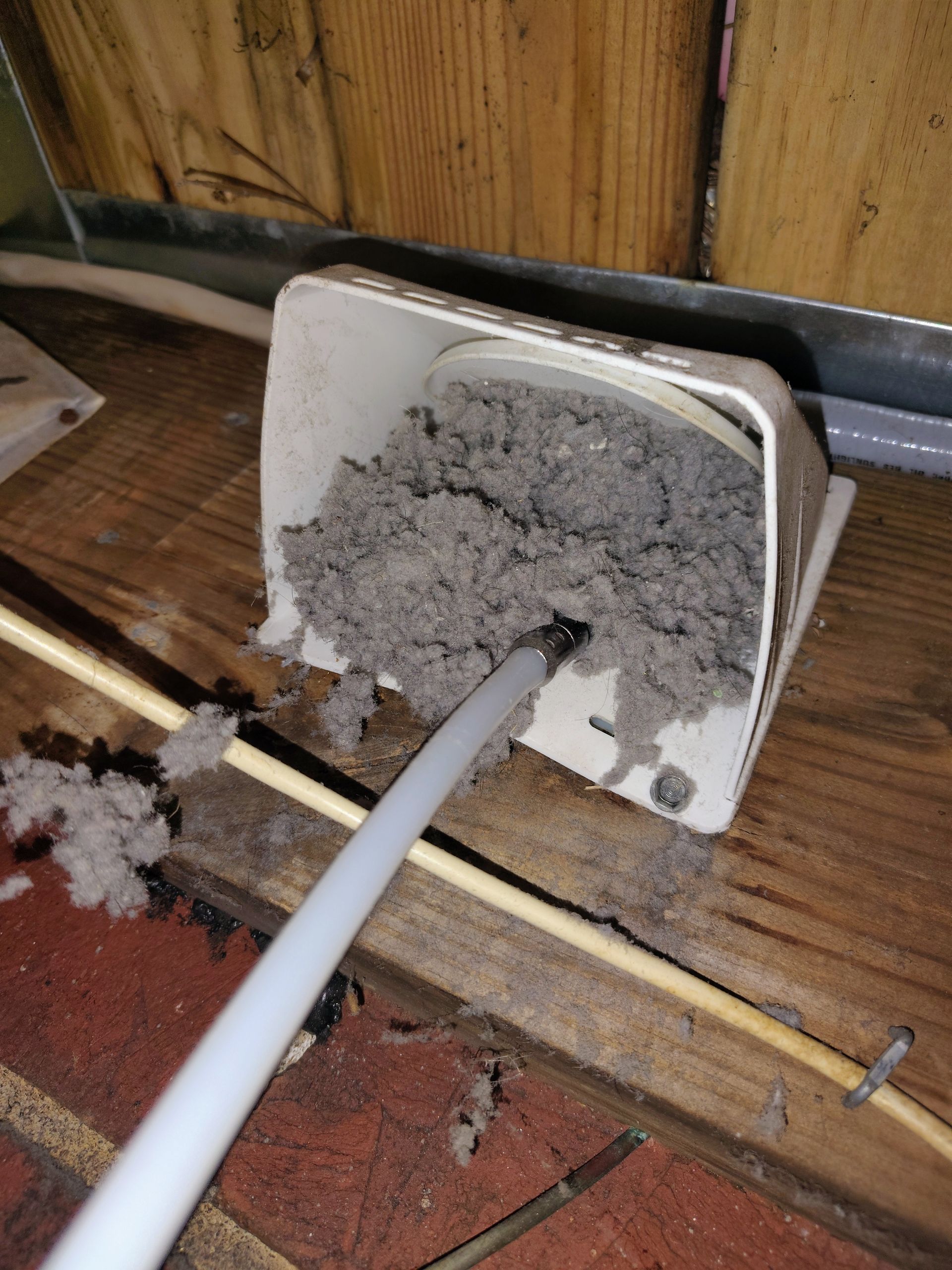 Metal vent on a wall, with a ladder to the right. Building exterior.