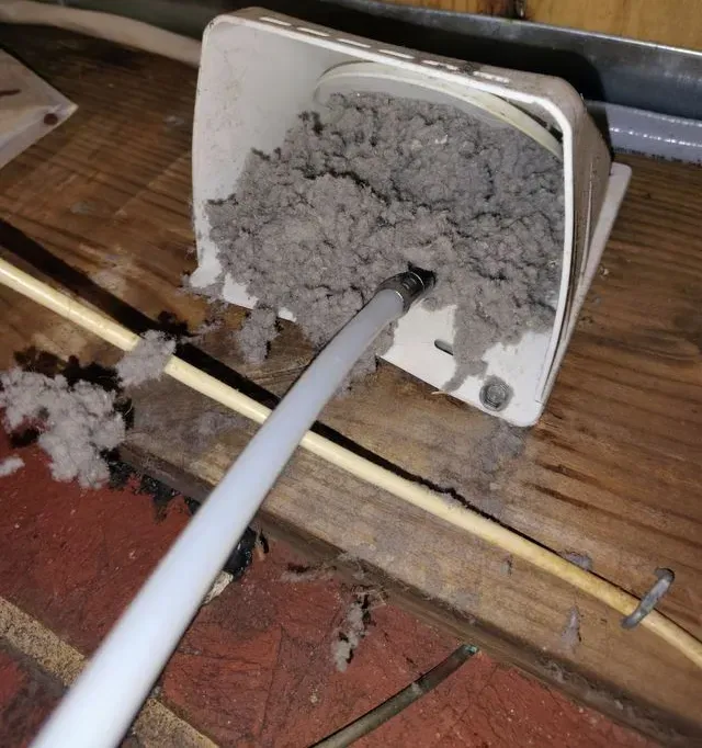 Metal vent on a wall, with a ladder to the right. Building exterior.