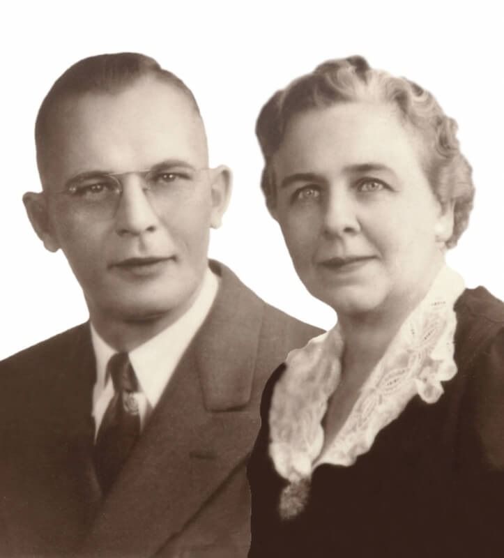 Portrait of a man and woman. The man wears glasses and a suit. The woman has curled hair and a lace collar.